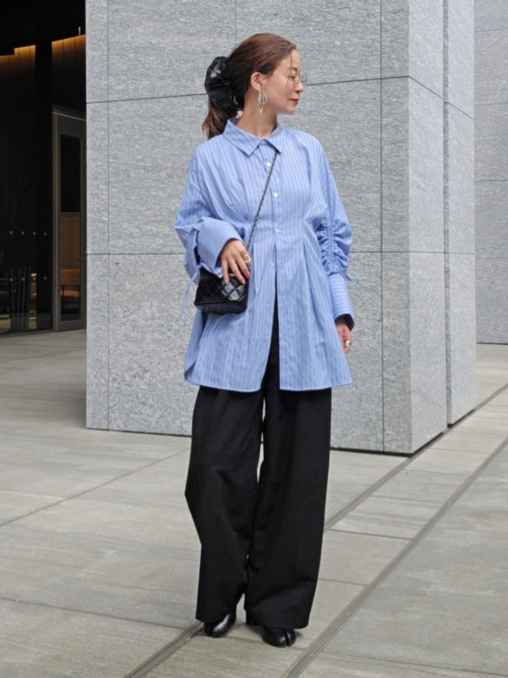 ブルー系のシャツ/ブラウス、ブラック系のスラックス、ブラック系のバッグを着用したレディースの春コーディネートの2枚目の写真