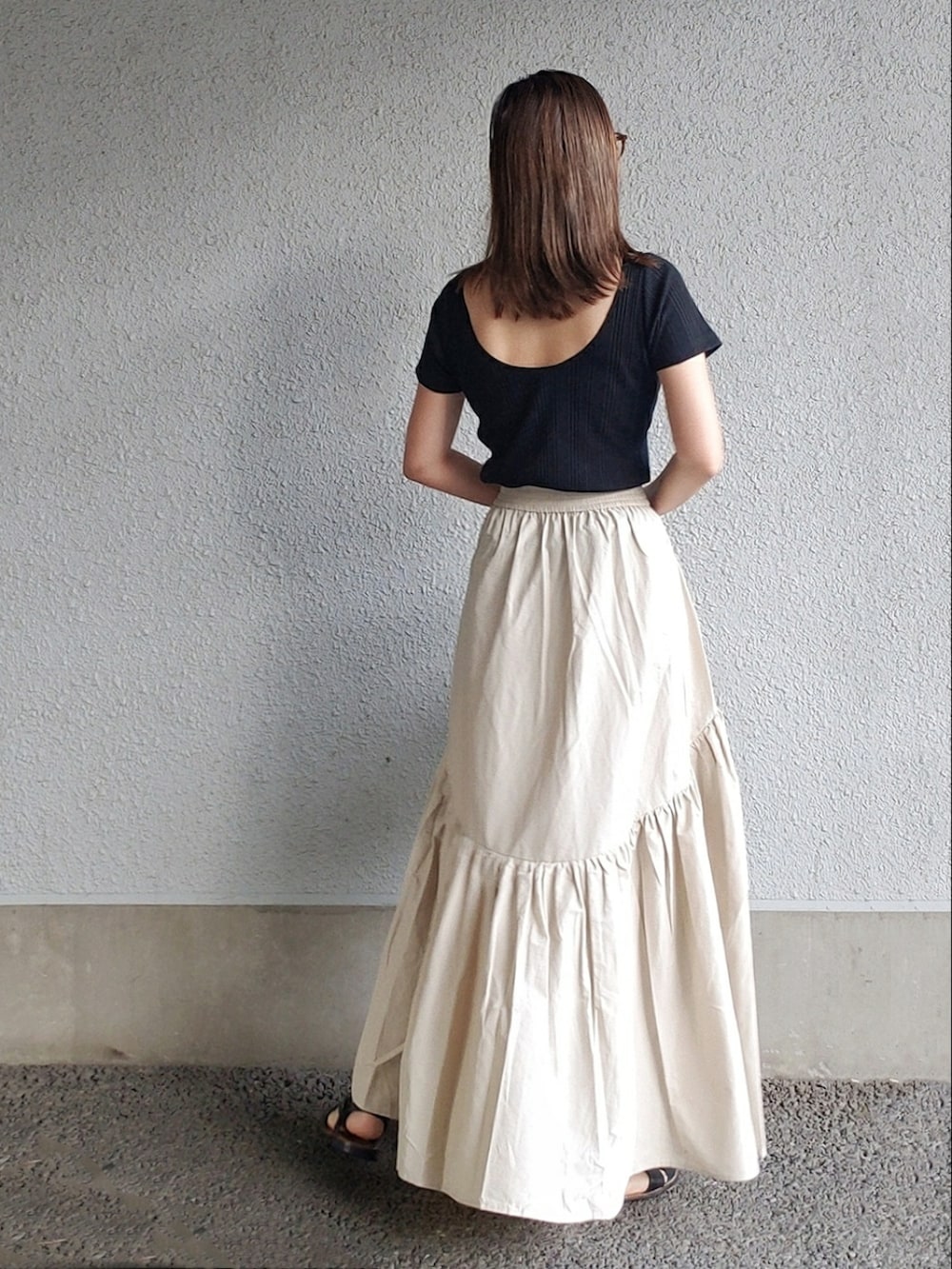 ホワイト系のスカート、ブラック系のTシャツ/カットソー、イエロー系のバッグを着用したレディースの夏コーディネートの2枚目の写真