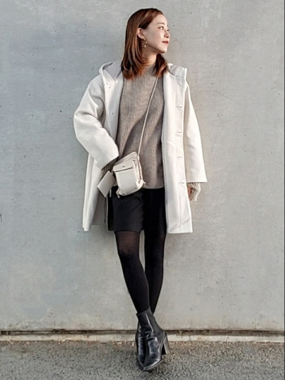 ホワイト系のその他アウター、ブラック系のブーツ、ホワイト系のショルダーバッグを着用したレディースの冬コーディネートの2枚目の写真