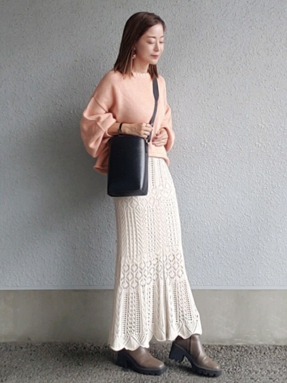 ピンク系のニット/セーター、ブラック系のバッグ、ホワイト系のスカートを着用したレディースの秋コーディネートの3枚目の写真