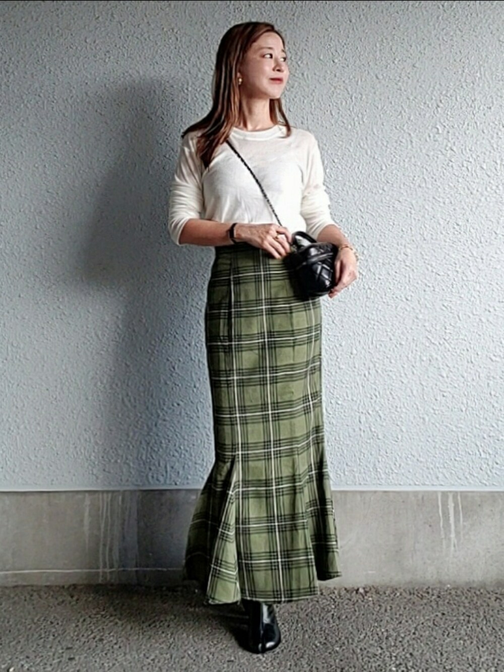 グリーン系のスカート、ブラック系のブーツ、ホワイト系のTシャツ/カットソーを着用したレディースの秋コーディネートの3枚目の写真