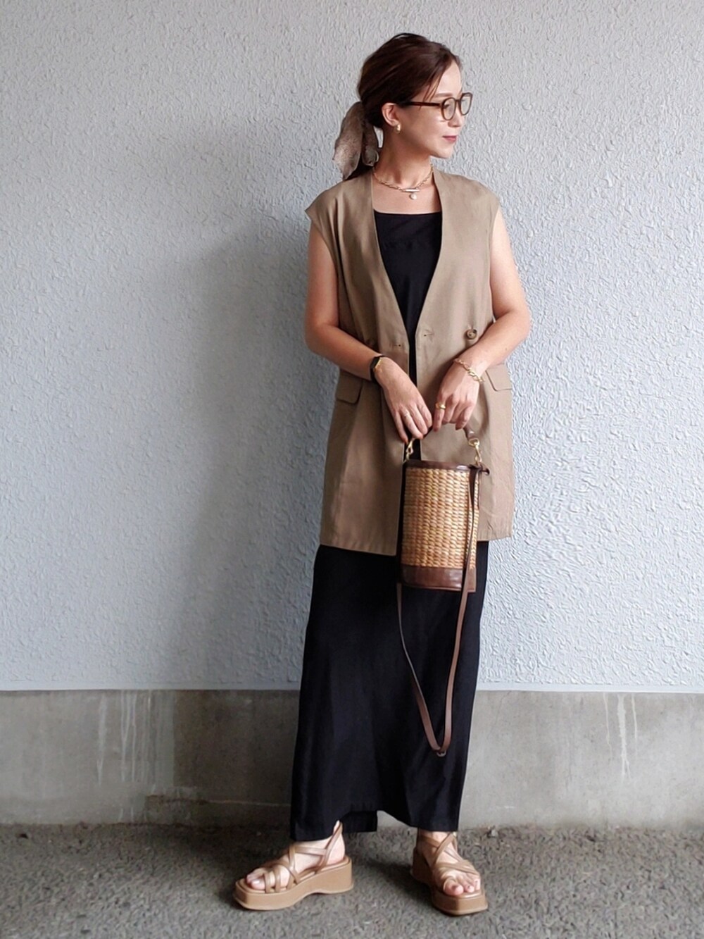 ブラック系のワンピース、ブラウン系のベスト、ブラウン系のサンダルを着用したレディースの夏コーディネートの3枚目の写真