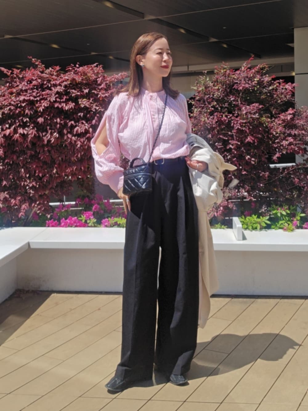 ピンク系のシャツ/ブラウス、ブラック系のスラックス、ブラック系のブーツを着用したレディースの春コーディネートの2枚目の写真