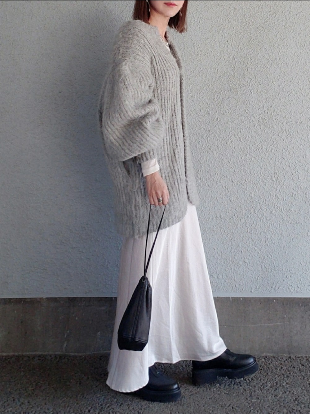 グレー系のカーディガン/ボレロ、ブラック系のバッグ、ベージュ系のスカートを着用したレディースの冬コーディネートの5枚目の写真