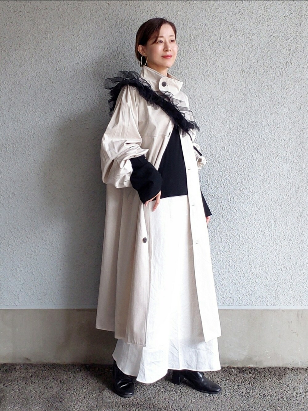 ホワイト系のトレンチコート、ホワイト系のスカート、ブラック系のTシャツ/カットソーを着用したレディースの冬コーディネートの3枚目の写真