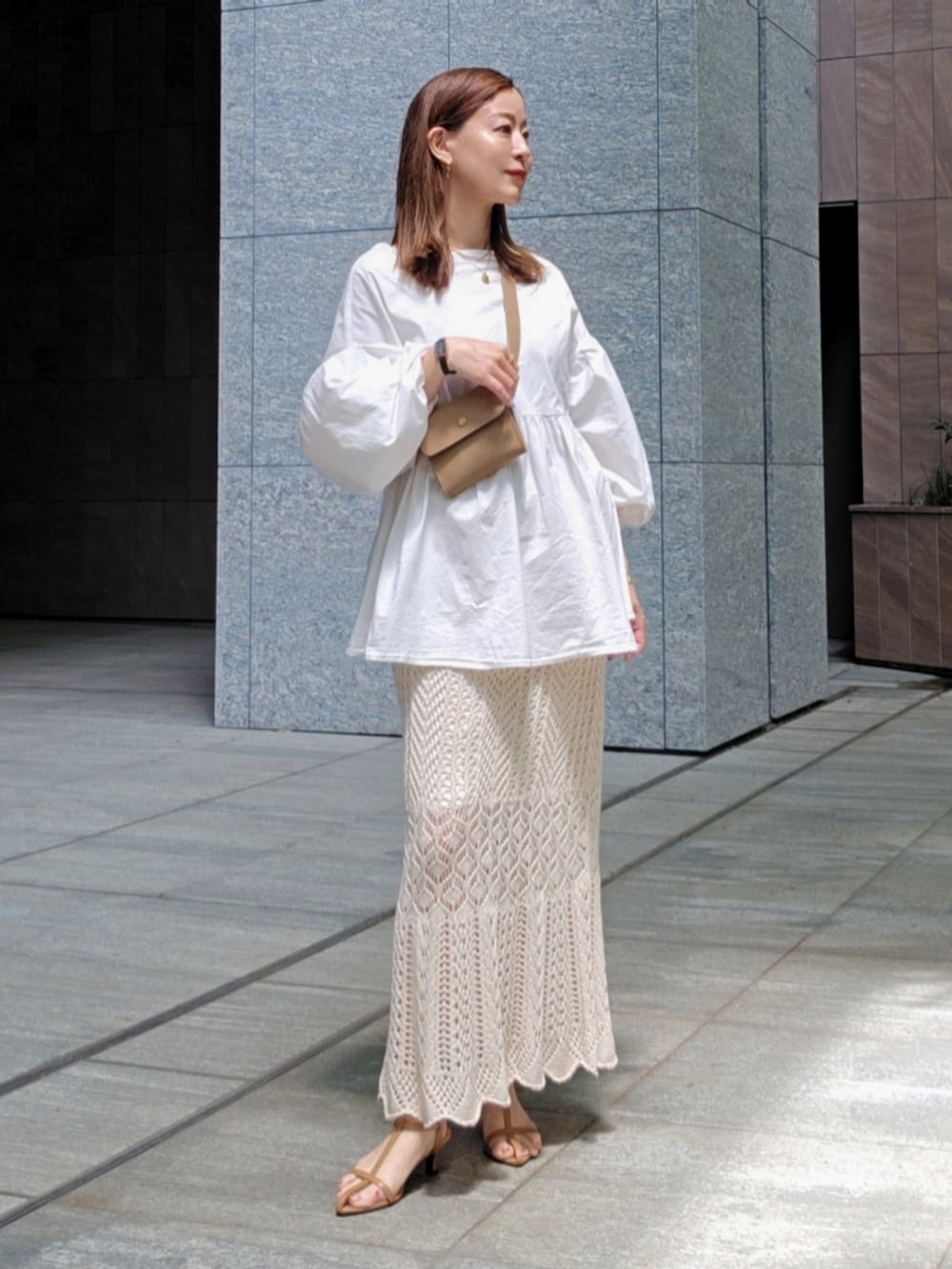 ベージュ系のショルダーバッグ、ホワイト系のスカート、ホワイト系のシャツ/ブラウスを着用したレディースの春コーディネートの2枚目の写真