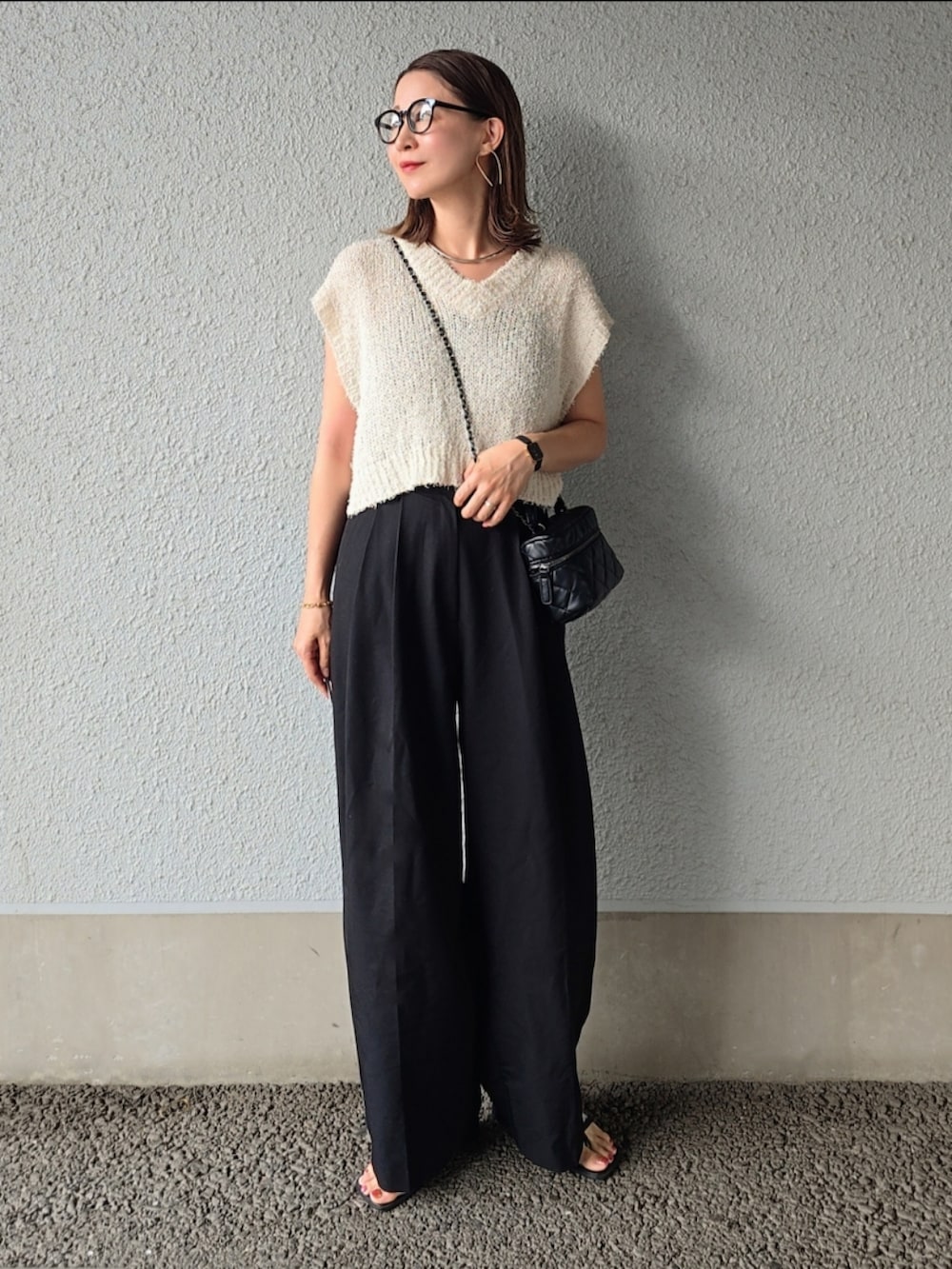 ホワイト系のトップス、ブラック系のスラックス、ブラック系のバッグを着用したレディースの夏コーディネートの3枚目の写真