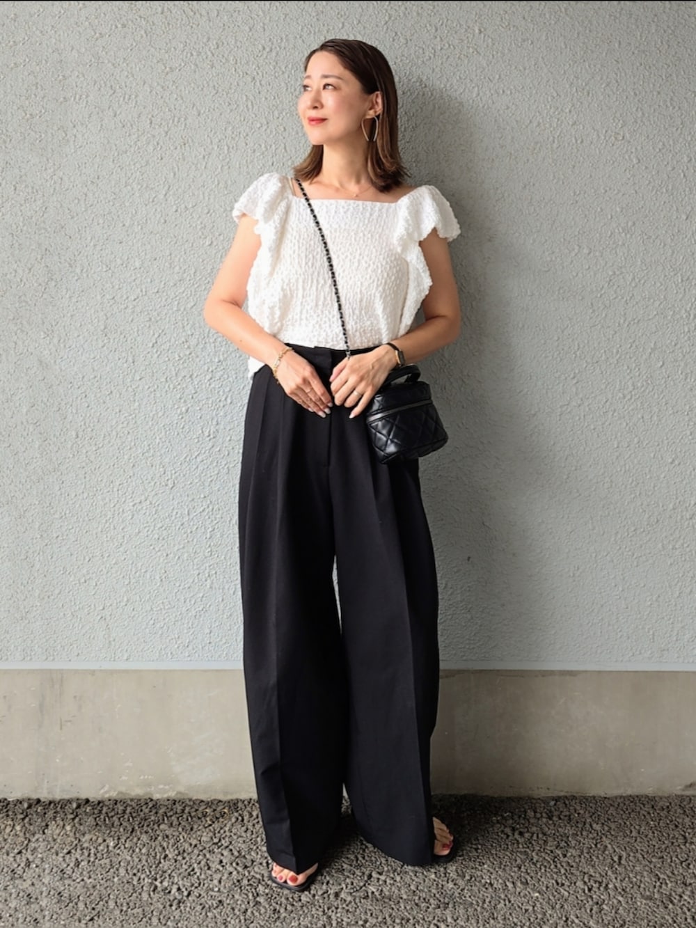 ホワイト系のシャツ/ブラウス、ブラック系のスラックス、ブラック系のサンダルを着用したレディースの夏コーディネートの3枚目の写真