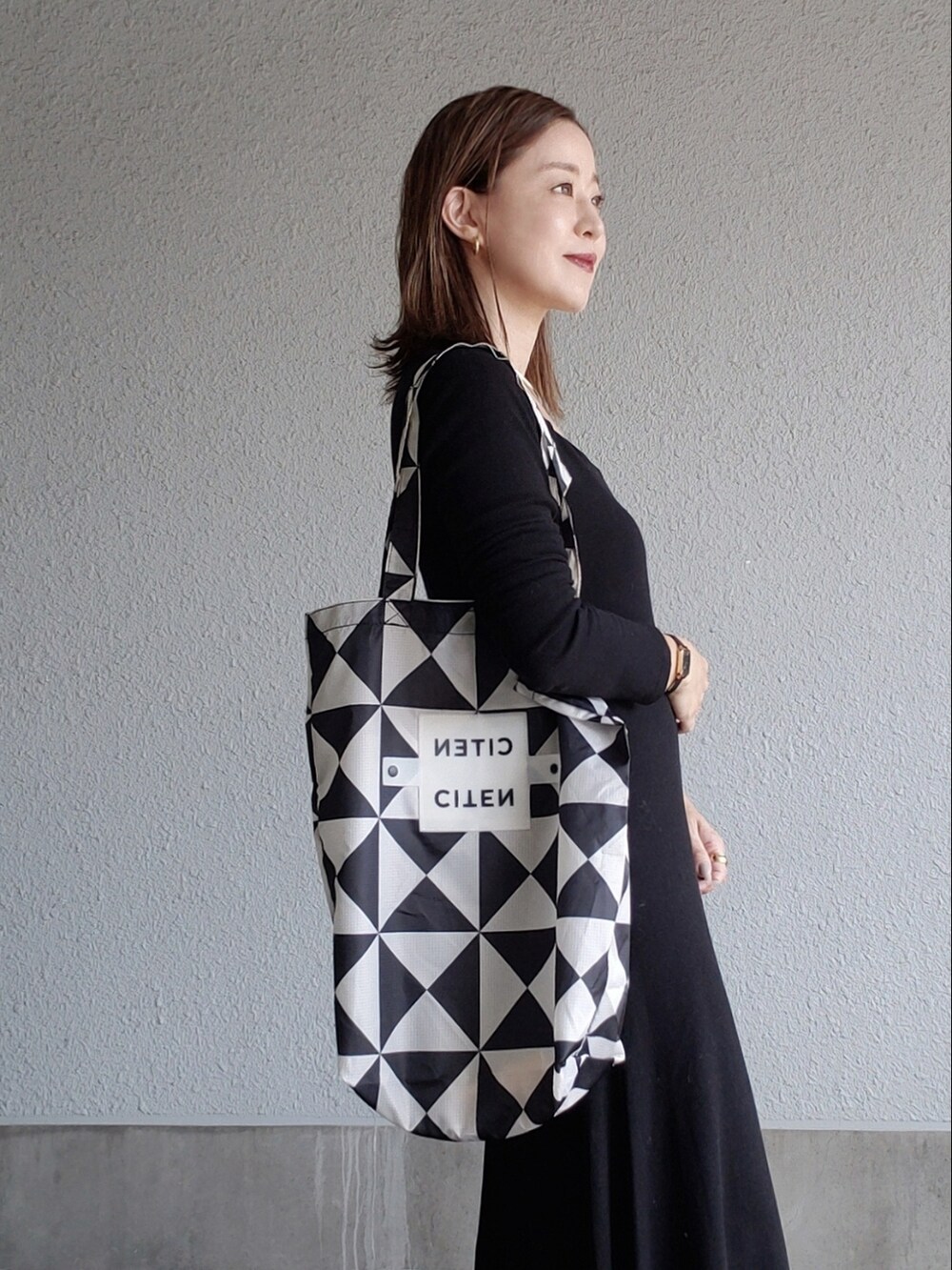 ブラック系のワンピース、ベージュ系のブーツ、ブラック系のトートバッグを着用したレディースの秋コーディネートの2枚目の写真