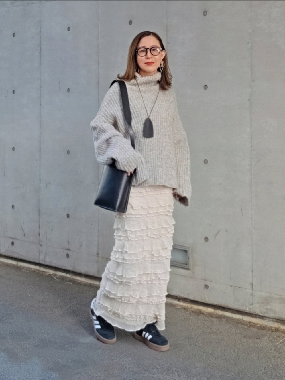 グレー系のニット/セーター、ホワイト系のスカート、ブラック系のバッグを着用したレディースの冬コーディネートの4枚目の写真