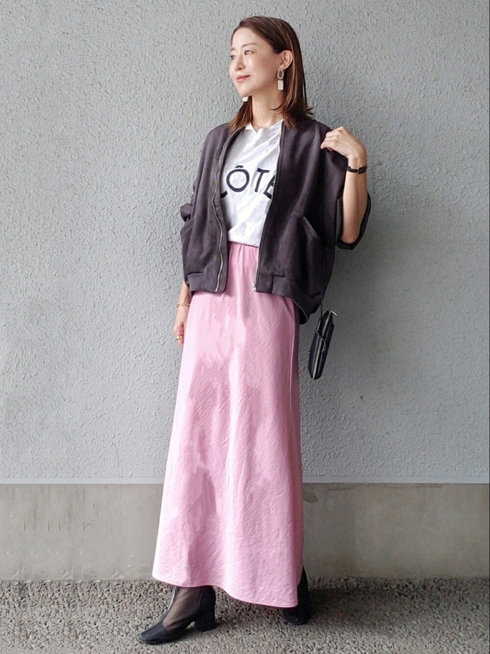 ブラック系のブルゾン、ピンク系のスカート、ブラック系のブーツを着用したレディースの秋コーディネートの3枚目の写真