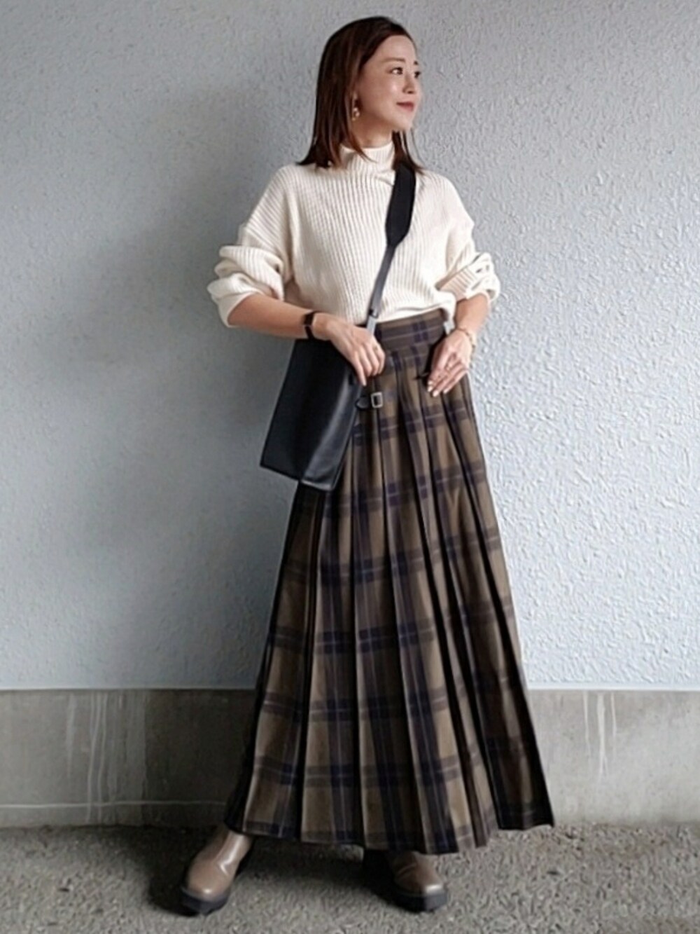 グリーン系のスカート、ホワイト系のニット/セーター、ベージュ系のブーツを着用したレディースの秋コーディネートの2枚目の写真