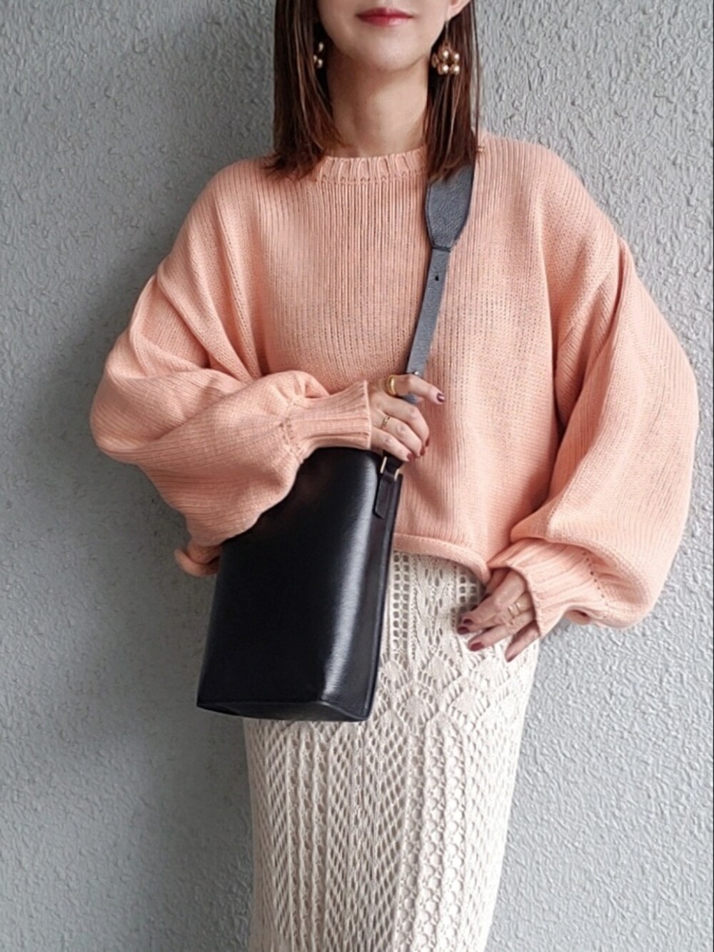 ピンク系のニット/セーター、ブラック系のバッグ、ホワイト系のスカートを着用したレディースの秋コーディネートの2枚目の写真