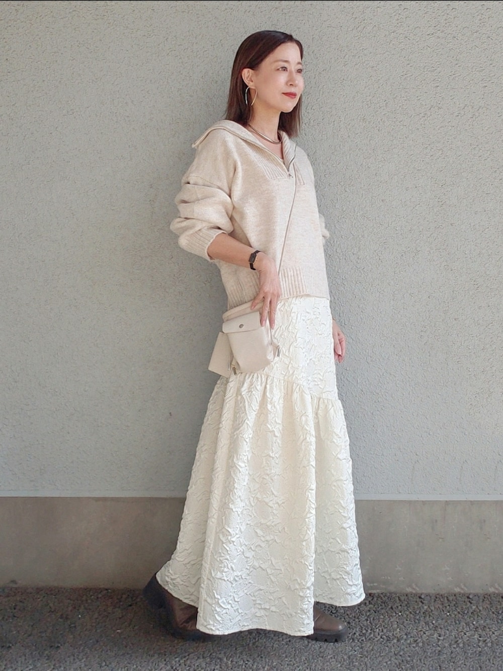 ベージュ系のトップス、ホワイト系のスカート、ベージュ系のブーツを着用したレディースの冬コーディネートの3枚目の写真