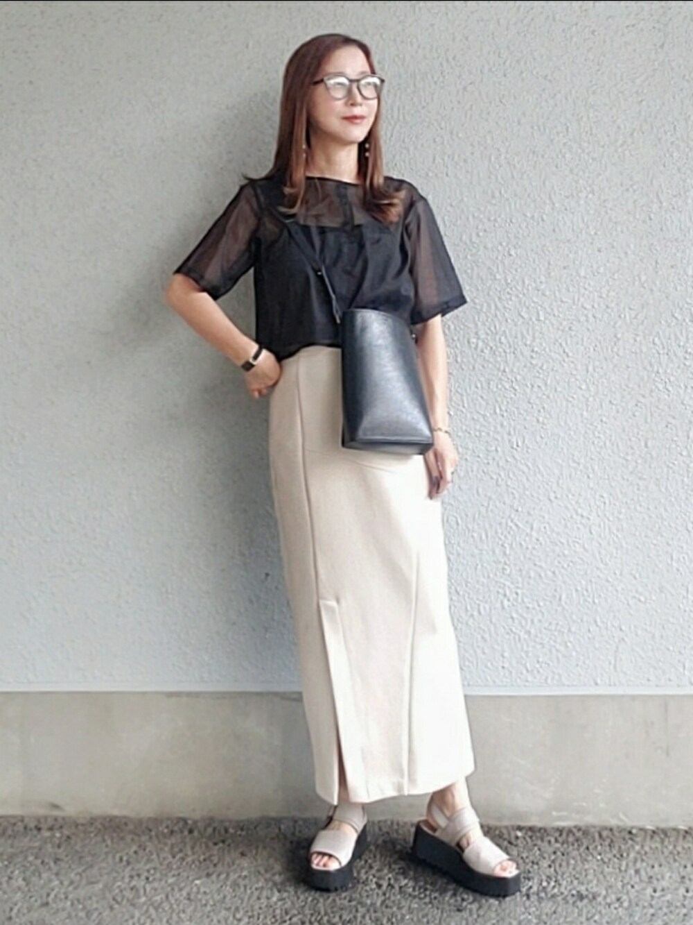 ブラック系のトップス、ベージュ系のスカート、グレー系のサンダルを着用したレディースの夏コーディネートの3枚目の写真