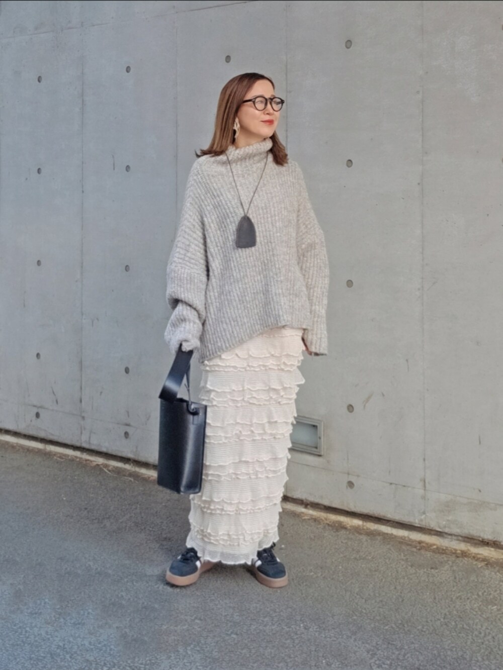 グレー系のニット/セーター、ホワイト系のスカート、ブラック系のバッグを着用したレディースの冬コーディネートの3枚目の写真