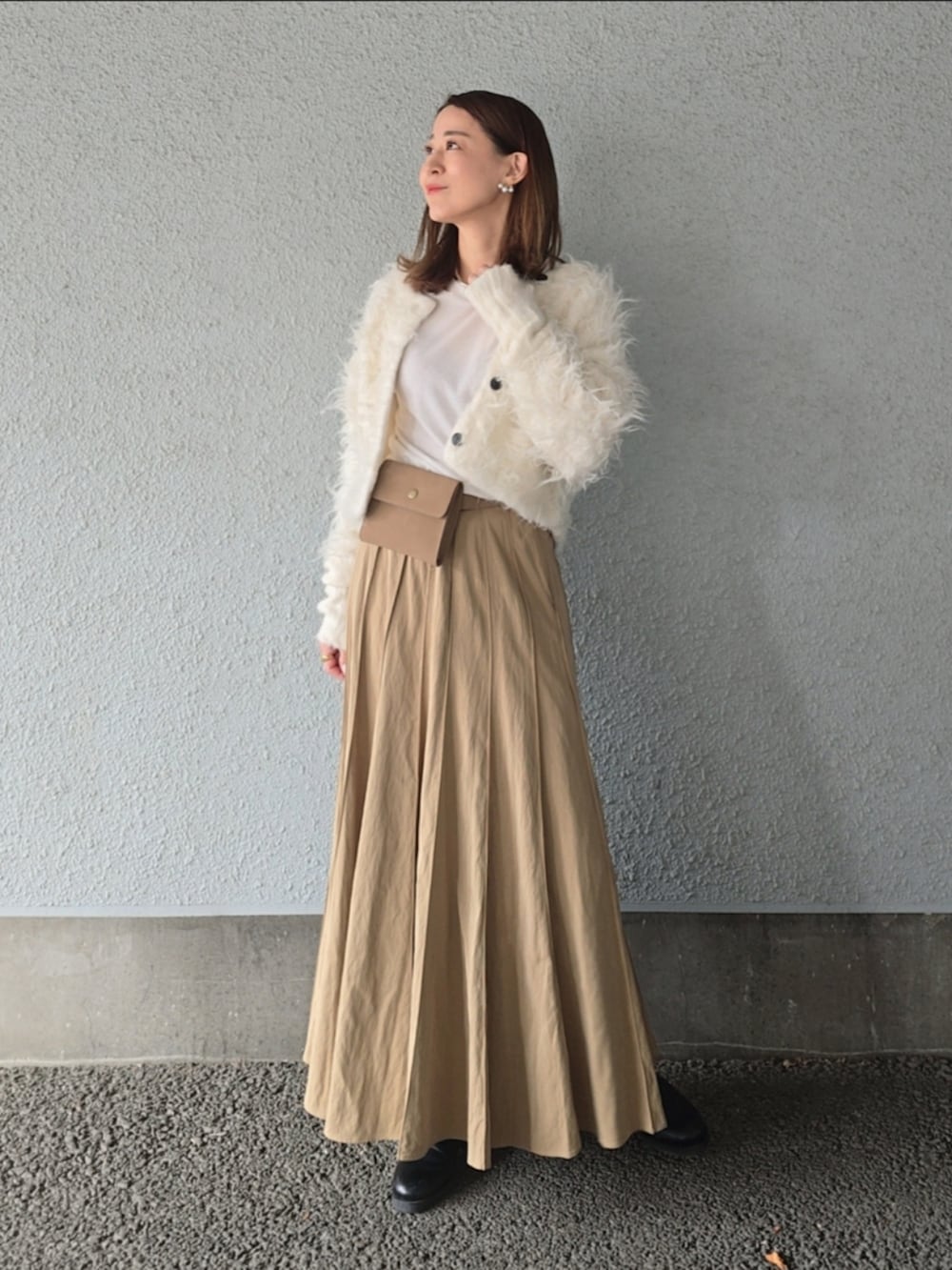 ベージュ系のスカート、ホワイト系のカーディガン/ボレロ、ベージュ系のショルダーバッグを着用したレディースの秋コーディネートの2枚目の写真