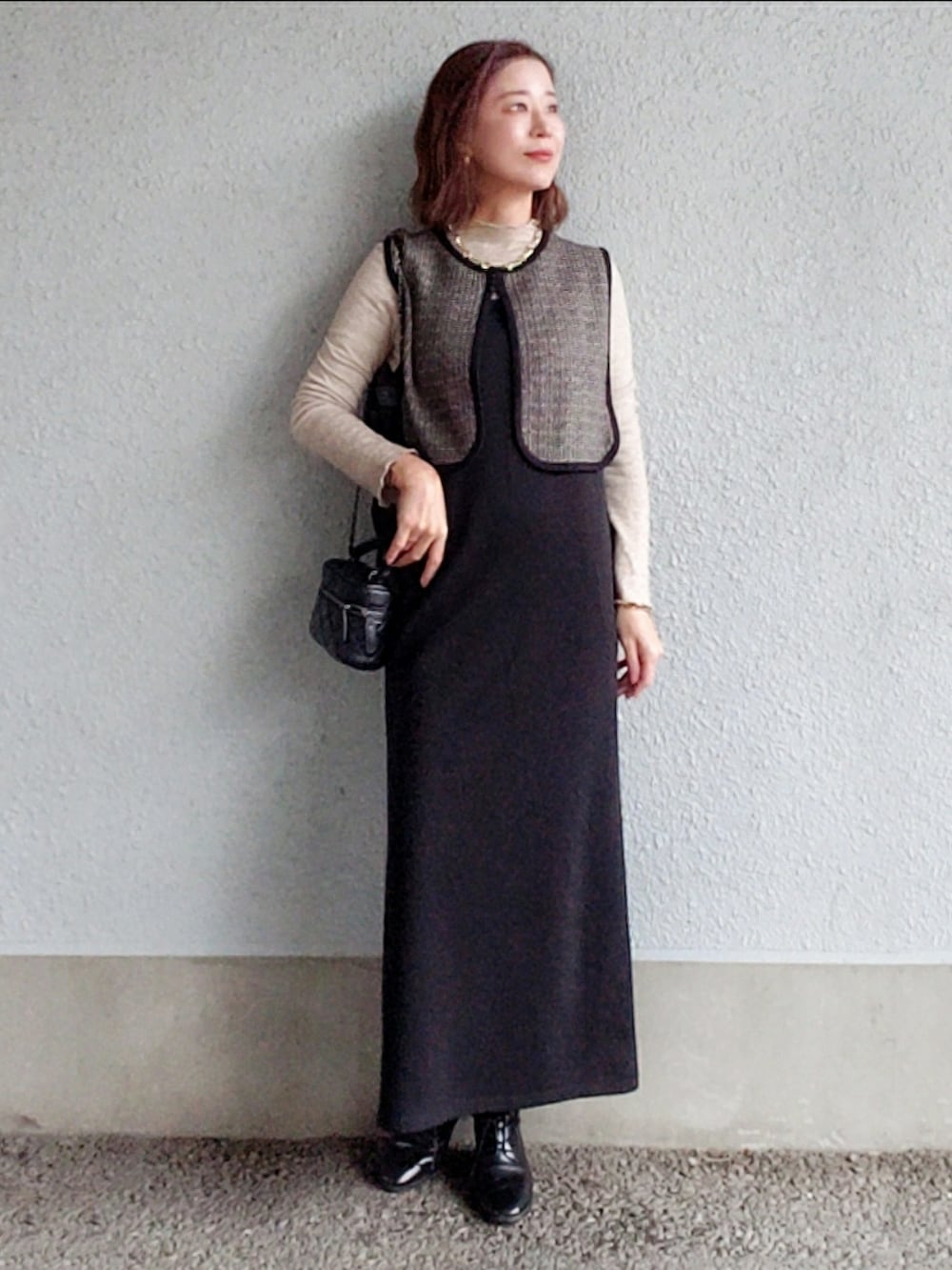 ブラック系のワンピース、ブラック系のベスト、ブラック系のブーツを着用したレディースの冬コーディネートの2枚目の写真