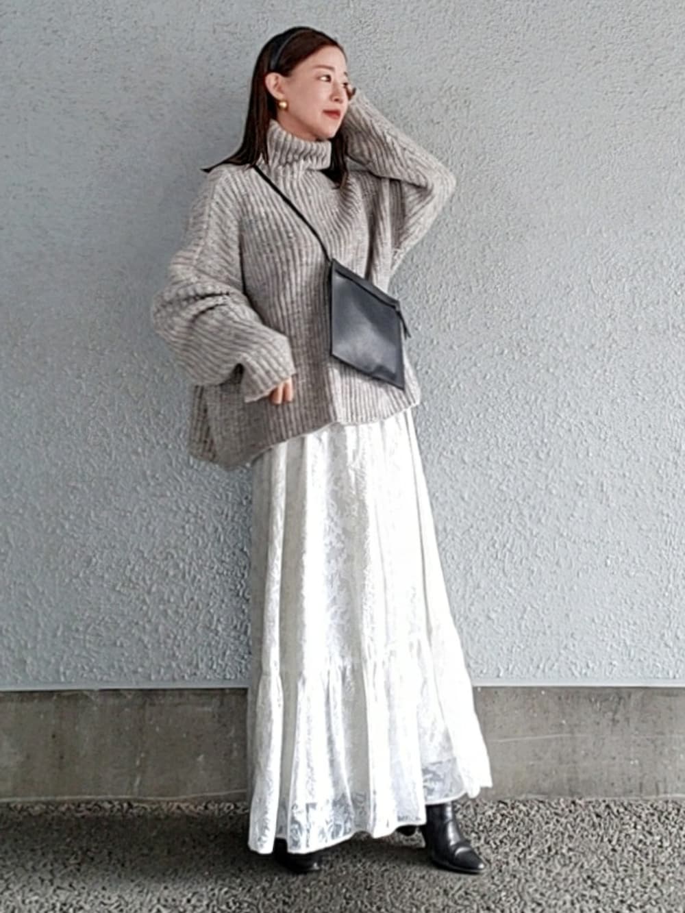 グレー系のニット/セーター、ホワイト系のスカート、ブラック系のブーツを着用したレディースの冬コーディネートの3枚目の写真