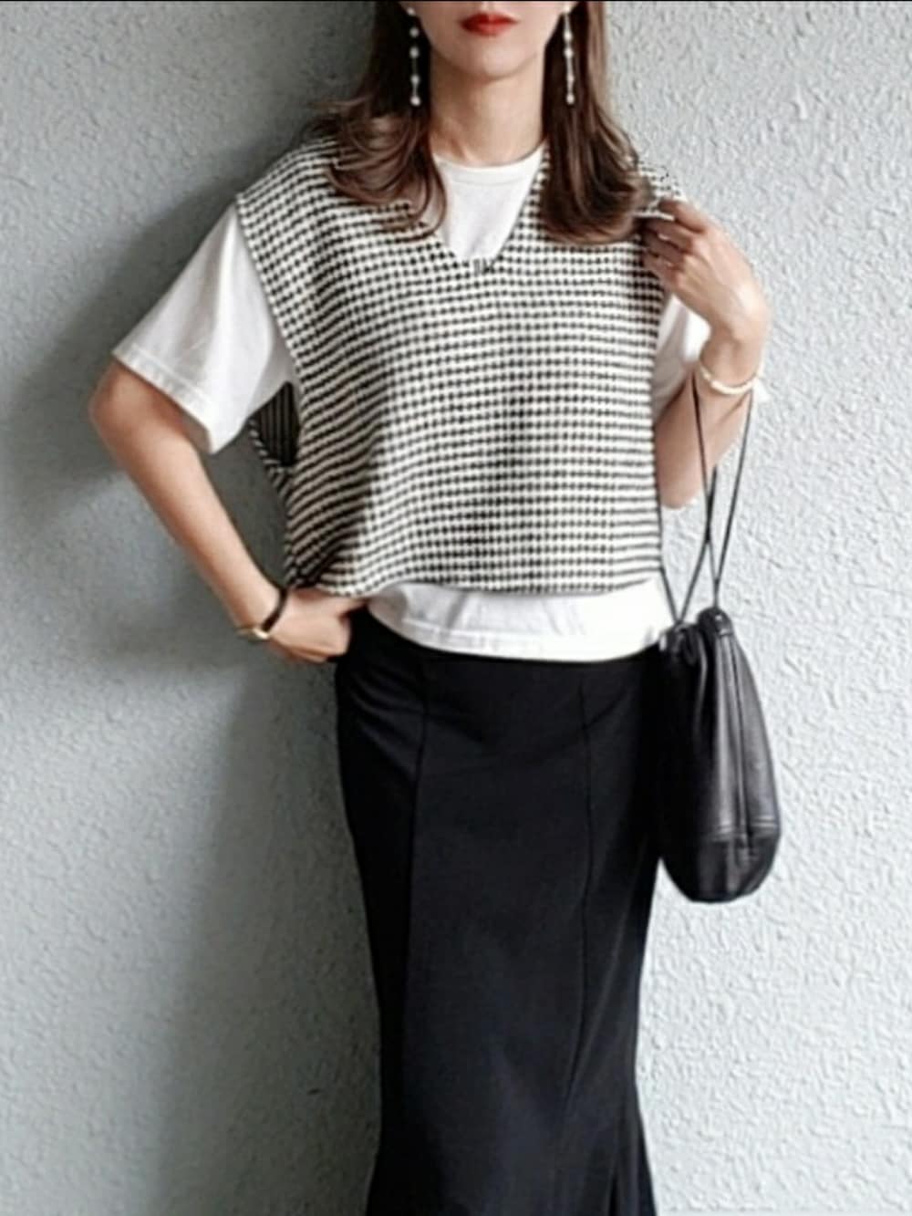 ブラック系のベスト、ブラック系のスカート、ブラック系のサンダルを着用したレディースの春コーディネートの2枚目の写真