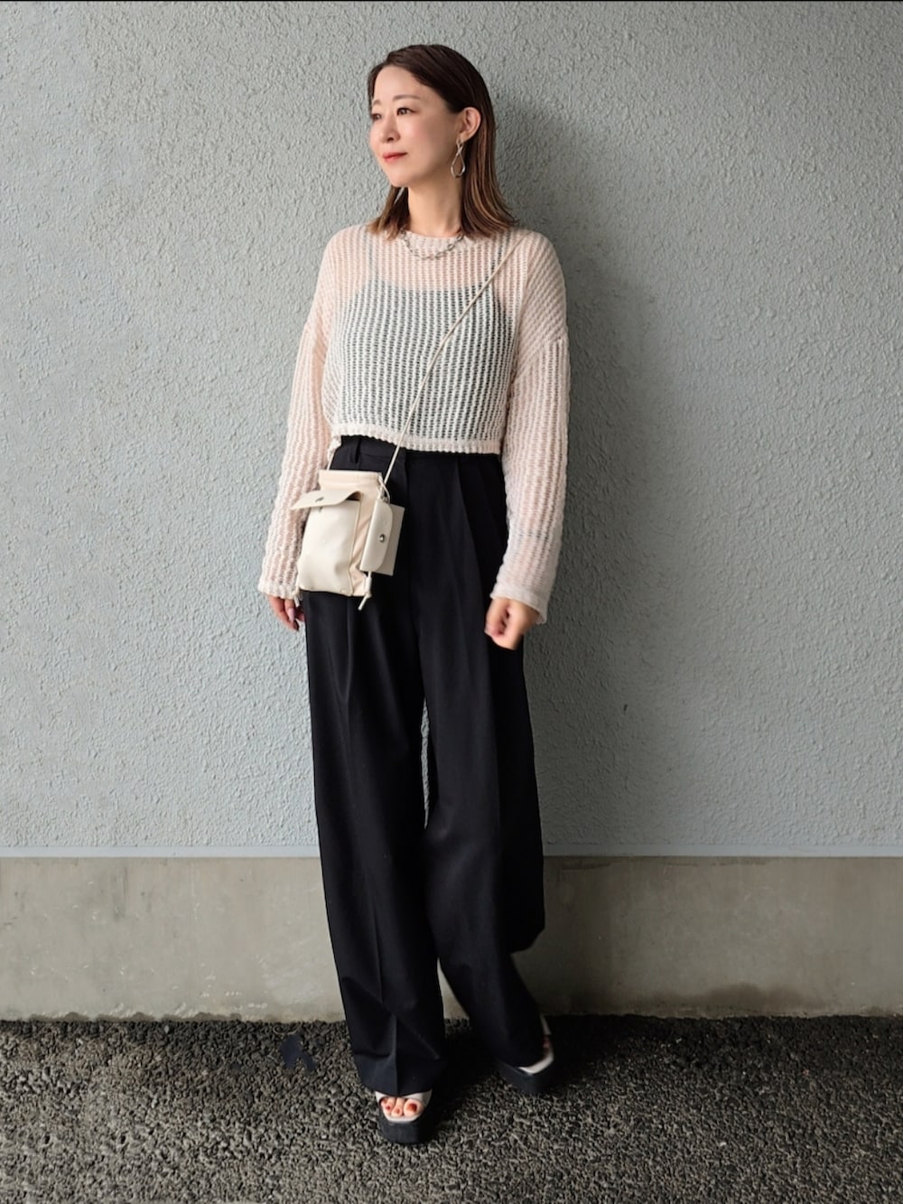 ベージュ系のニット/セーター、ブラック系のスラックス、グレー系のサンダルを着用したレディースの春コーディネートの2枚目の写真
