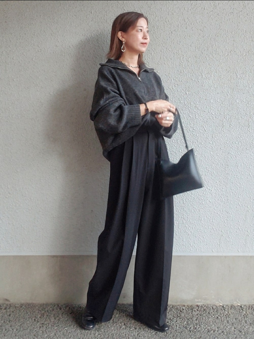 ブラック系のスラックス、ブラック系のブーツ、シルバー系のピアス（両耳用）を着用したレディースの冬コーディネートの2枚目の写真