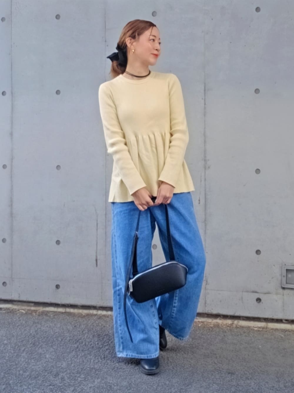 ブラック系のショルダーバッグ、ブルー系のデニムパンツを着用したレディースの春コーディネートの2枚目の写真