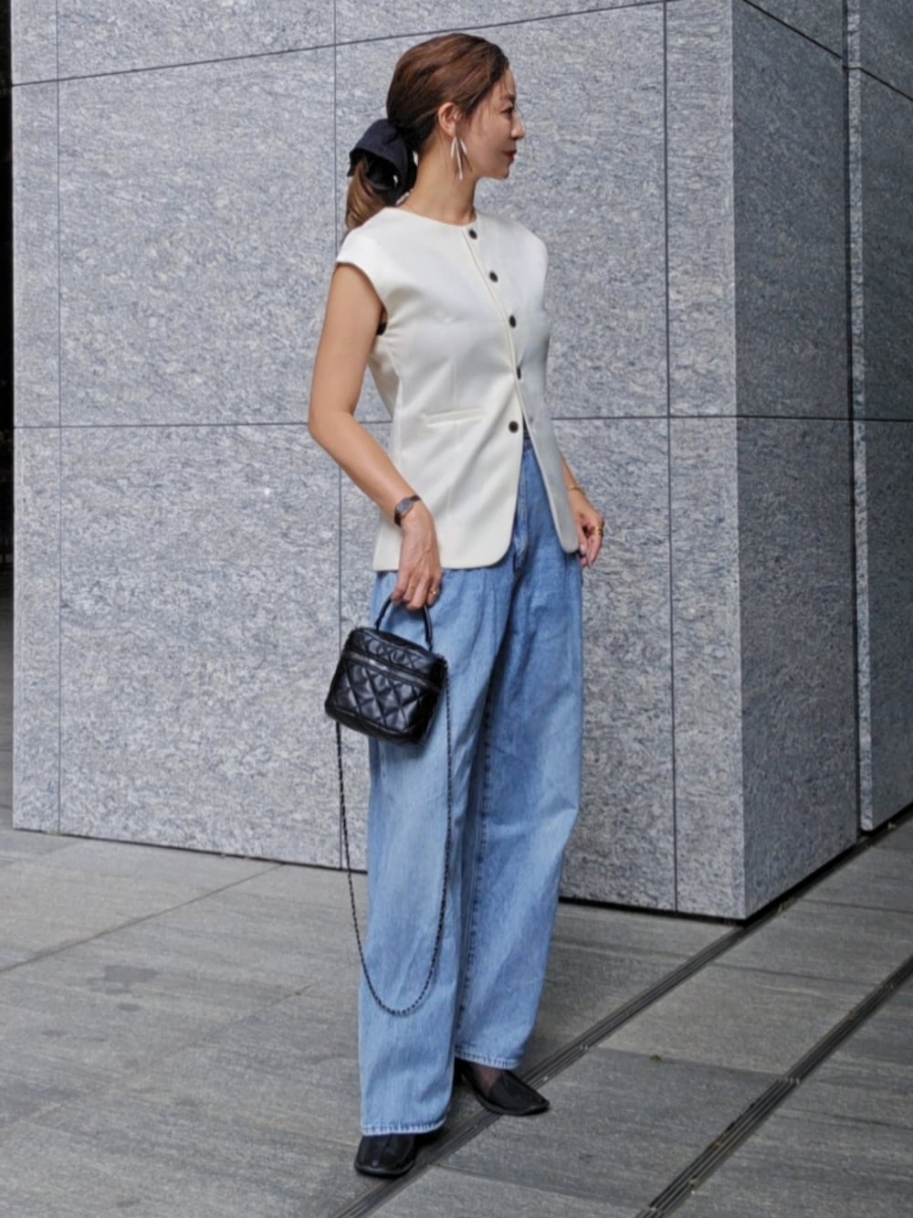 ホワイト系のベスト、ブルー系のデニムパンツ、ブラック系のブーツを着用したレディースの夏コーディネートの2枚目の写真