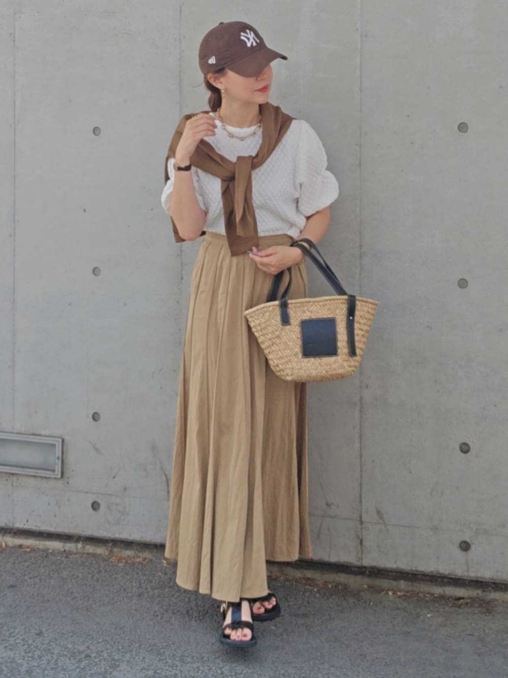 ベージュ系のスカート、ホワイト系のTシャツ/カットソー、ブラック系のかごバッグを着用したレディースの夏コーディネートの3枚目の写真