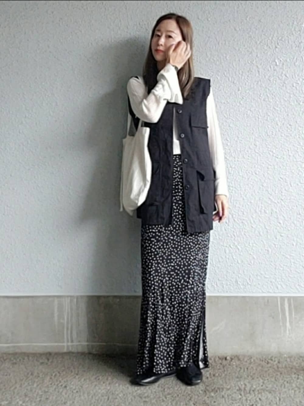 ブラック系のスカート、ブラック系のベスト、ブラック系のバレエシューズを着用したレディースの春コーディネートの3枚目の写真