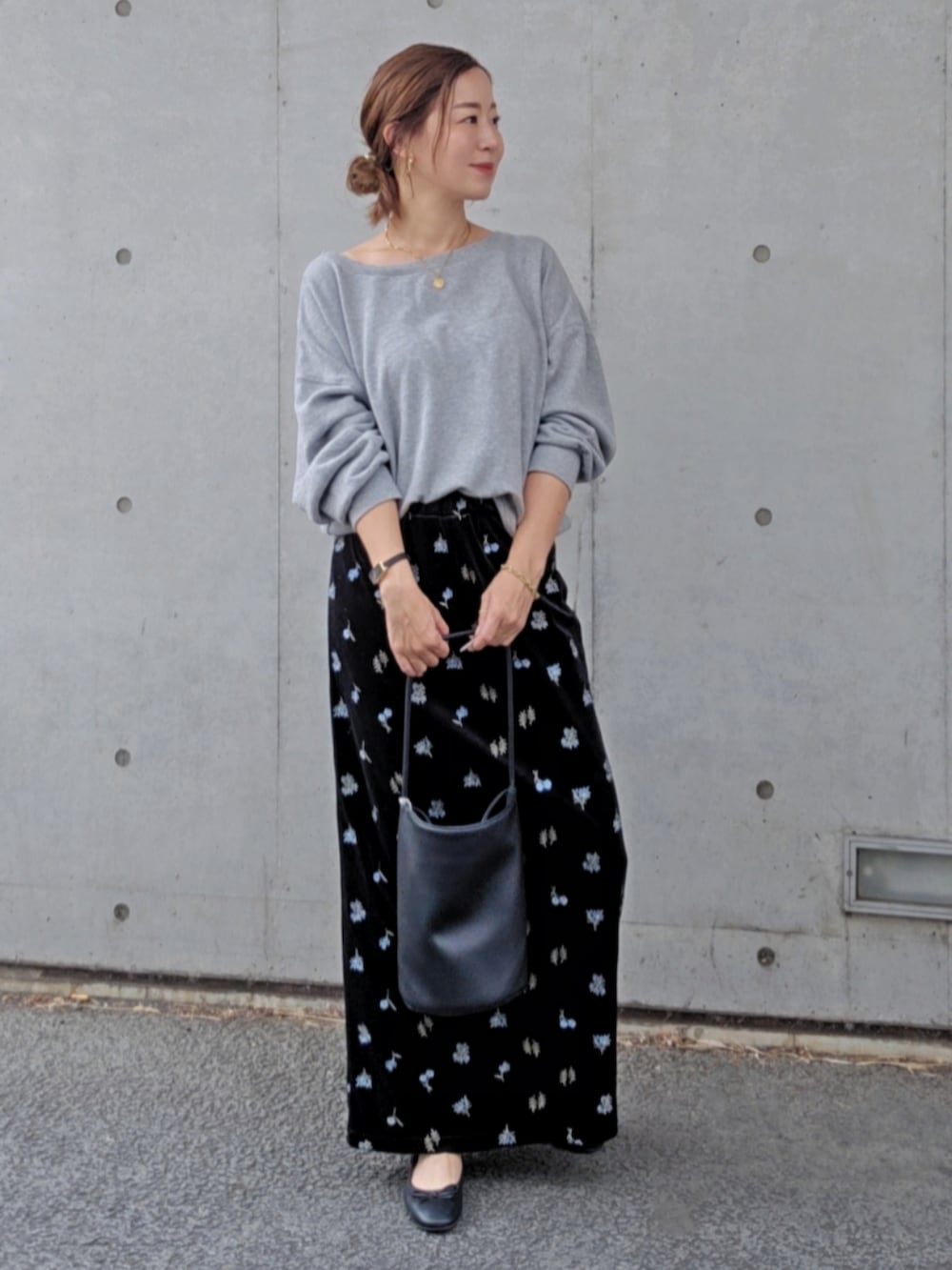 グレー系のスウェット、ブラック系のスカート、ブラック系のパンプスを着用したレディースの秋コーディネートの2枚目の写真