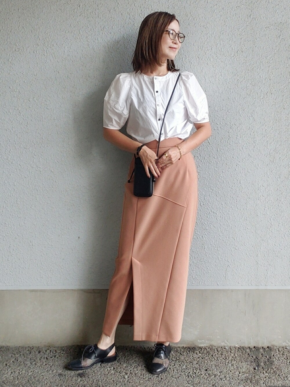 オレンジ系のスカート、ホワイト系のシャツ/ブラウス、ブラック系のドレスシューズを着用したレディースの夏コーディネートの2枚目の写真