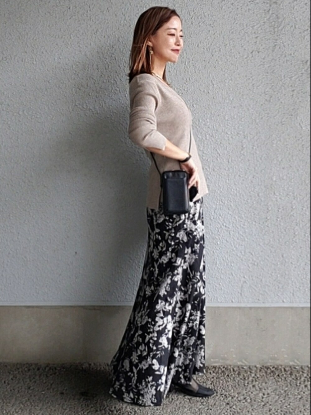 ブラック系のスカート、ベージュ系のニット/セーター、ブラック系のブーツを着用したレディースの秋コーディネートの2枚目の写真