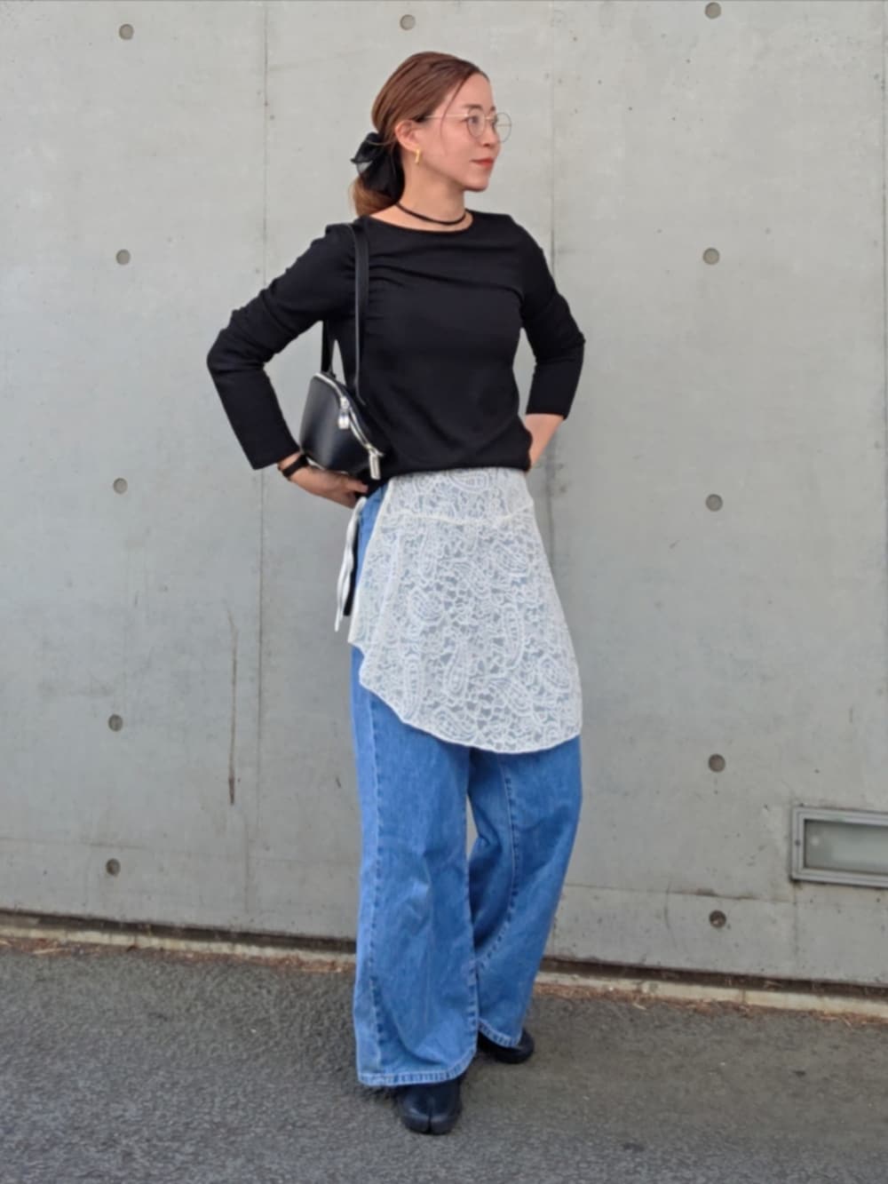 ブラック系のスニーカー、ブルー系のデニムパンツを着用したレディースの春コーディネートの3枚目の写真