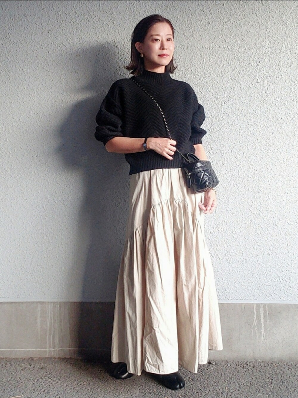 ブラック系のニット/セーター、ブラック系のバッグ、ベージュ系のトレンチコートを着用したレディースの秋コーディネートの4枚目の写真