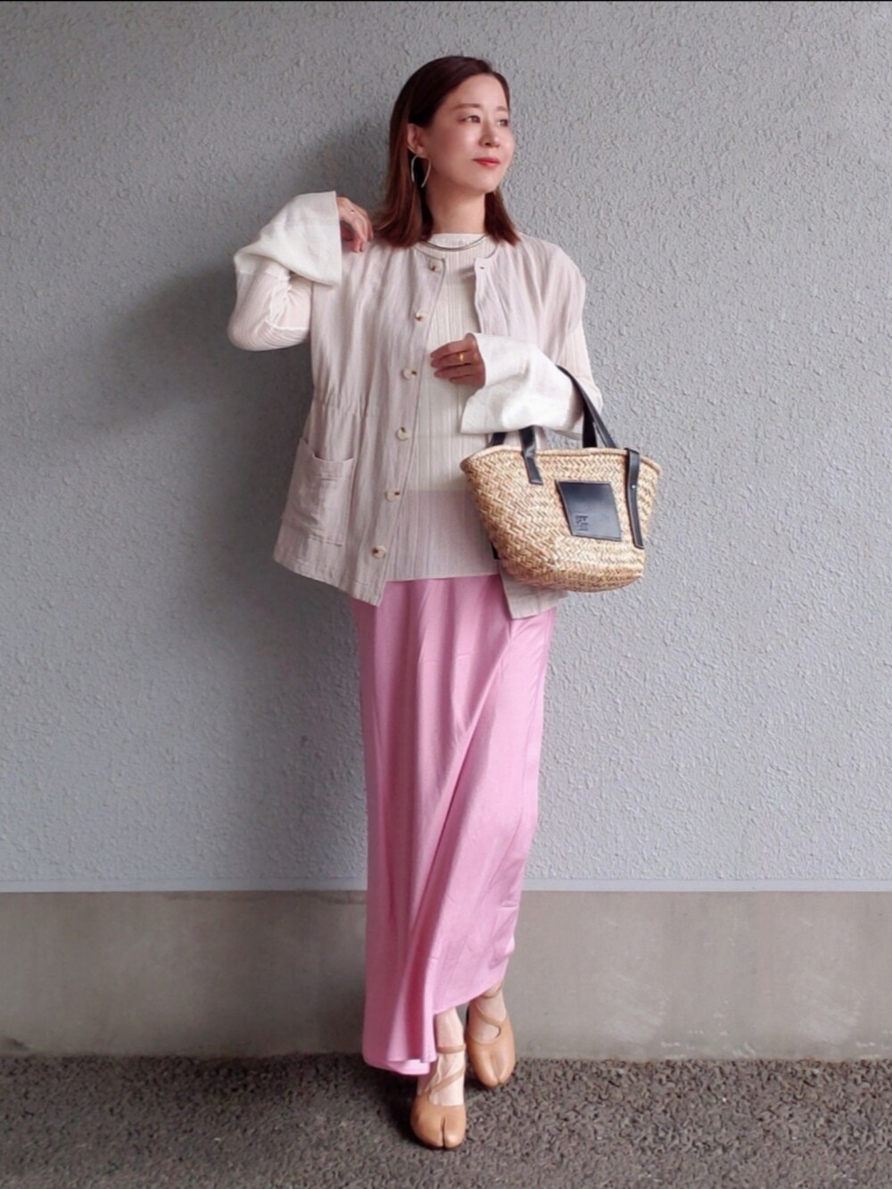 ピンク系のスカート、ブラック系のかごバッグ、ホワイト系のニット/セーターを着用したレディースの春コーディネートの3枚目の写真