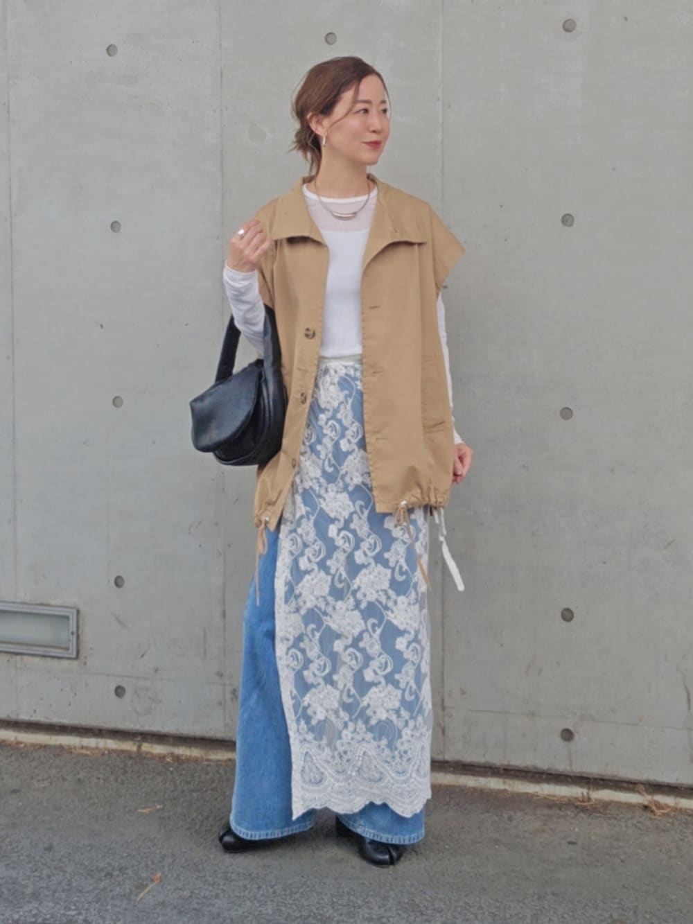 ホワイト系のスカート、ベージュ系のトレンチコート、ブルー系のデニムパンツを着用したレディースの春コーディネートの2枚目の写真