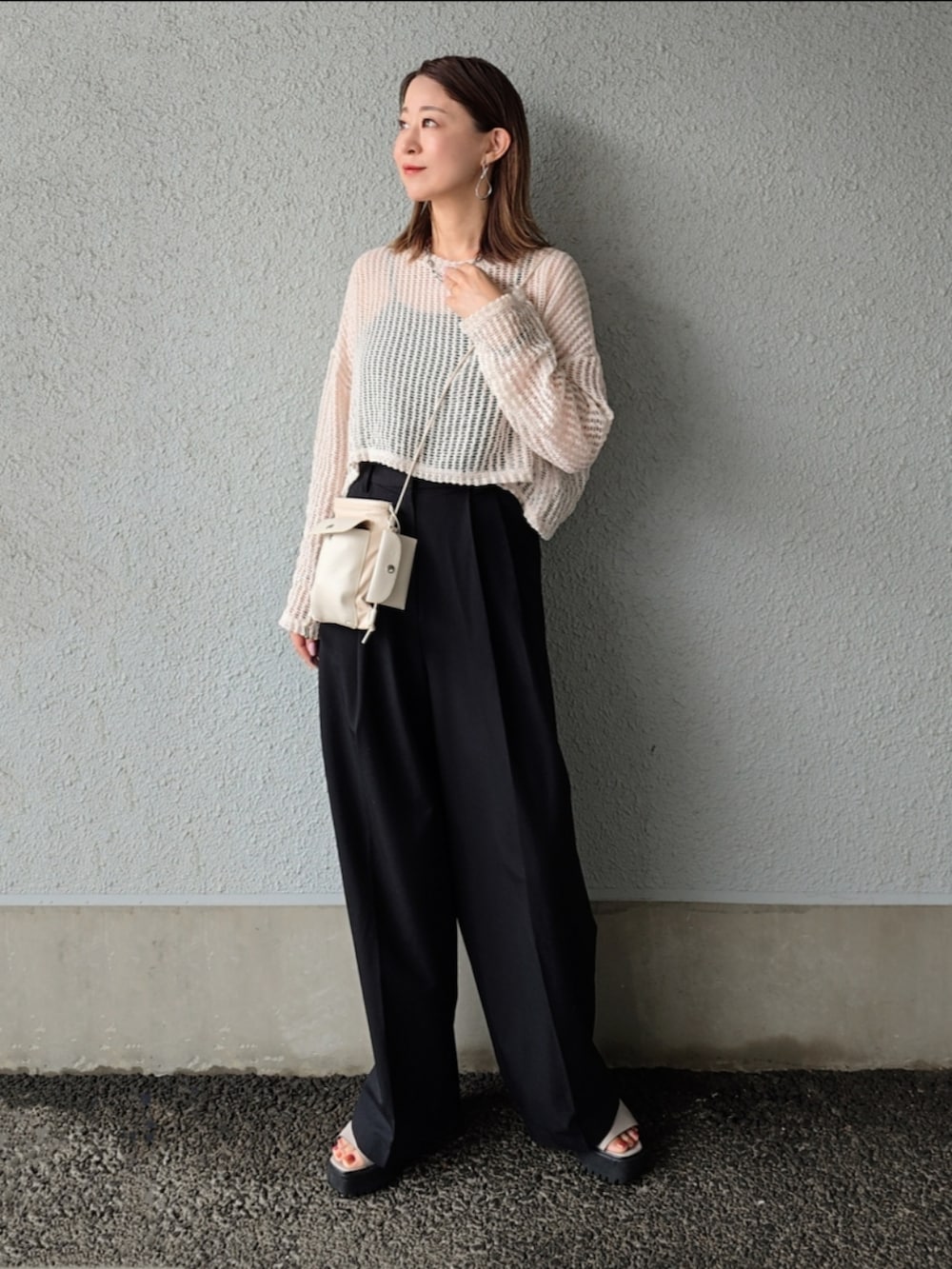 ベージュ系のニット/セーター、ブラック系のスラックス、グレー系のサンダルを着用したレディースの春コーディネートの3枚目の写真