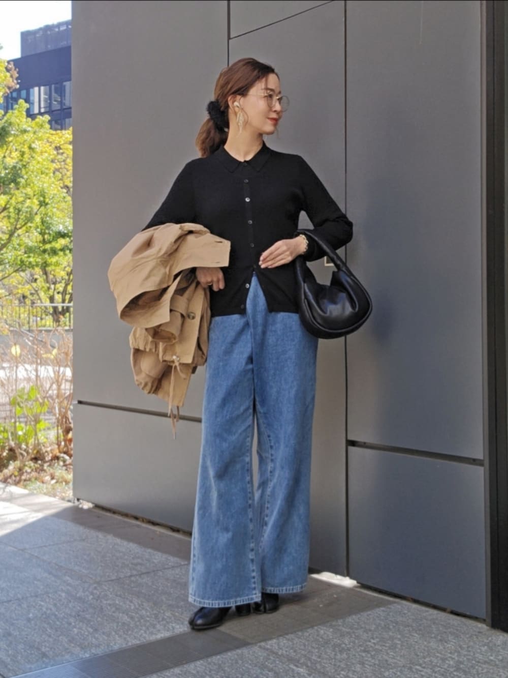 ベージュ系のトレンチコート、ブラック系のトップス、ブルー系のデニムパンツを着用したレディースの冬コーディネートの4枚目の写真