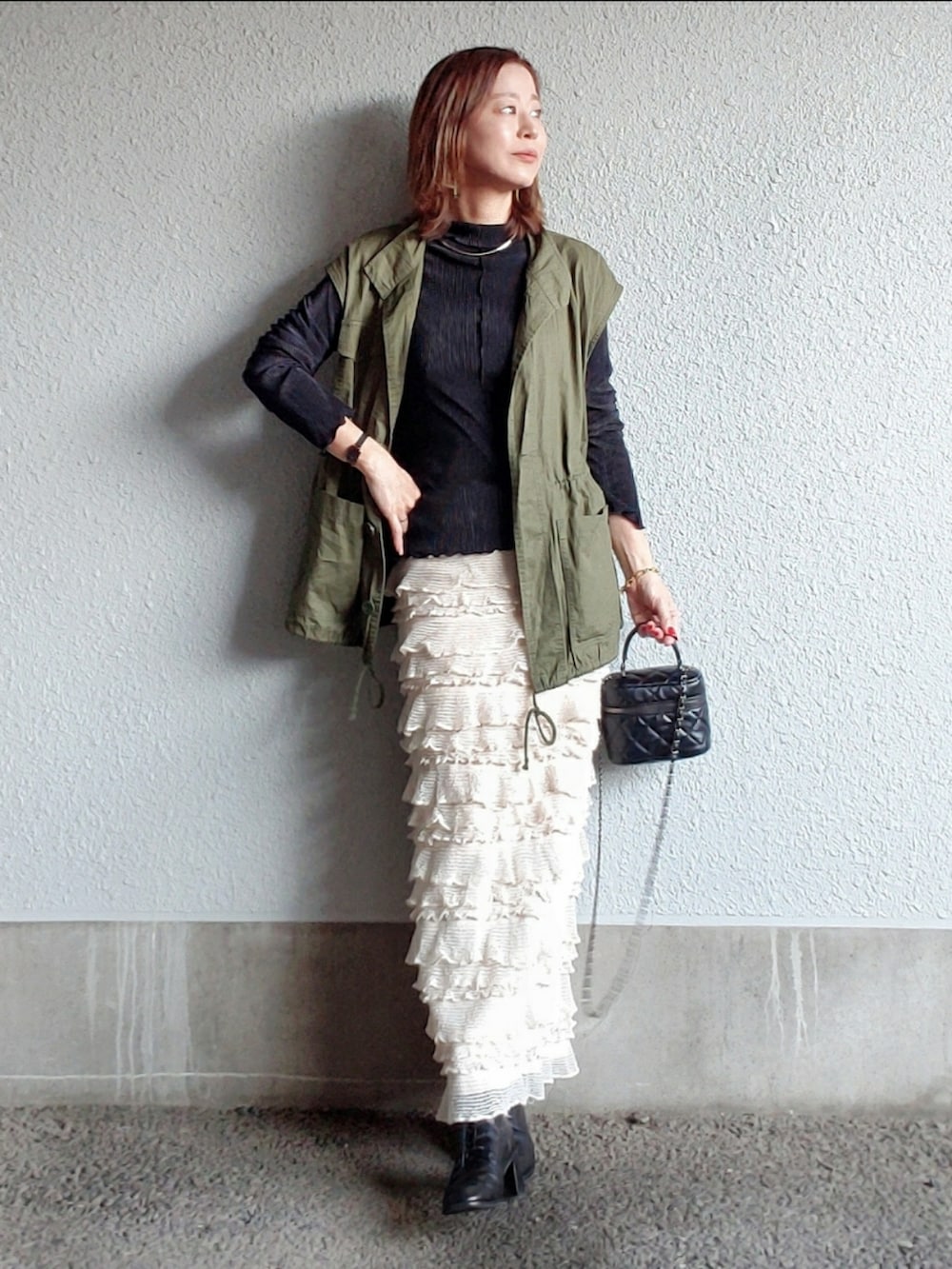 グリーン系のベスト、ホワイト系のスカート、ホワイト系のTシャツ/カットソーを着用したレディースの春コーディネートの2枚目の写真