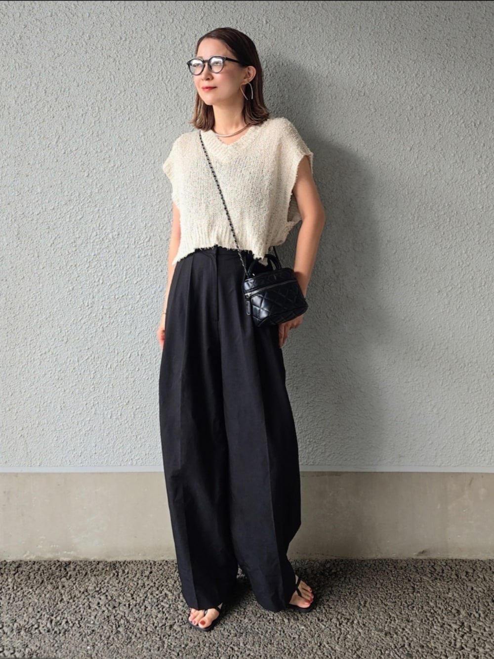 ホワイト系のトップス、ブラック系のスラックス、ブラック系のバッグを着用したレディースの夏コーディネートの2枚目の写真