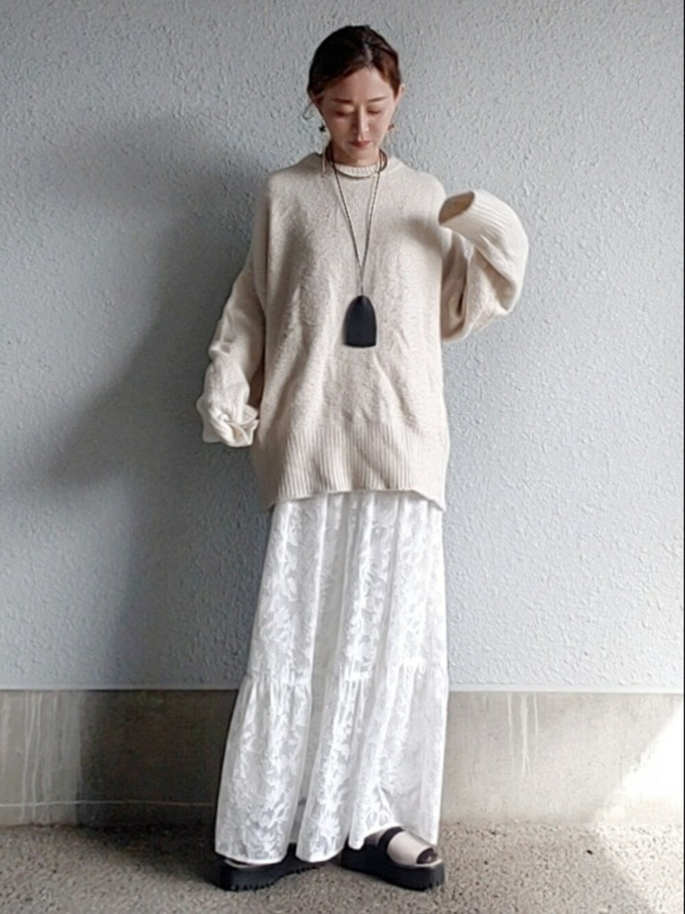 ホワイト系のニット/セーター、ホワイト系のスカート、グレー系のサンダルを着用したレディースの冬コーディネートの3枚目の写真