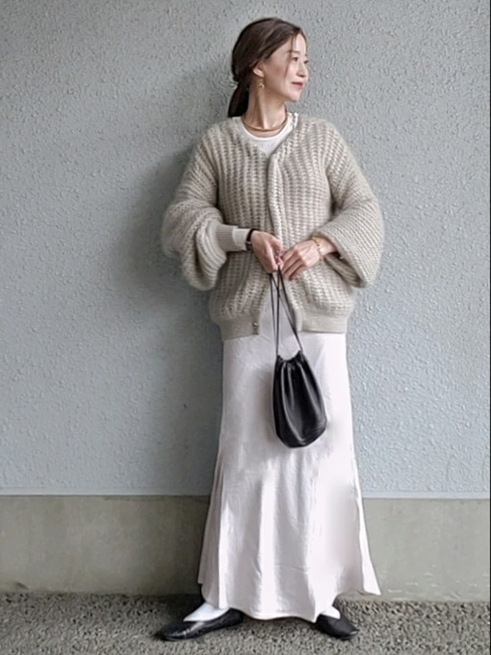 グレー系のカーディガン/ボレロ、ブラック系のバッグ、ホワイト系のスカートを着用したレディースの春コーディネートの2枚目の写真