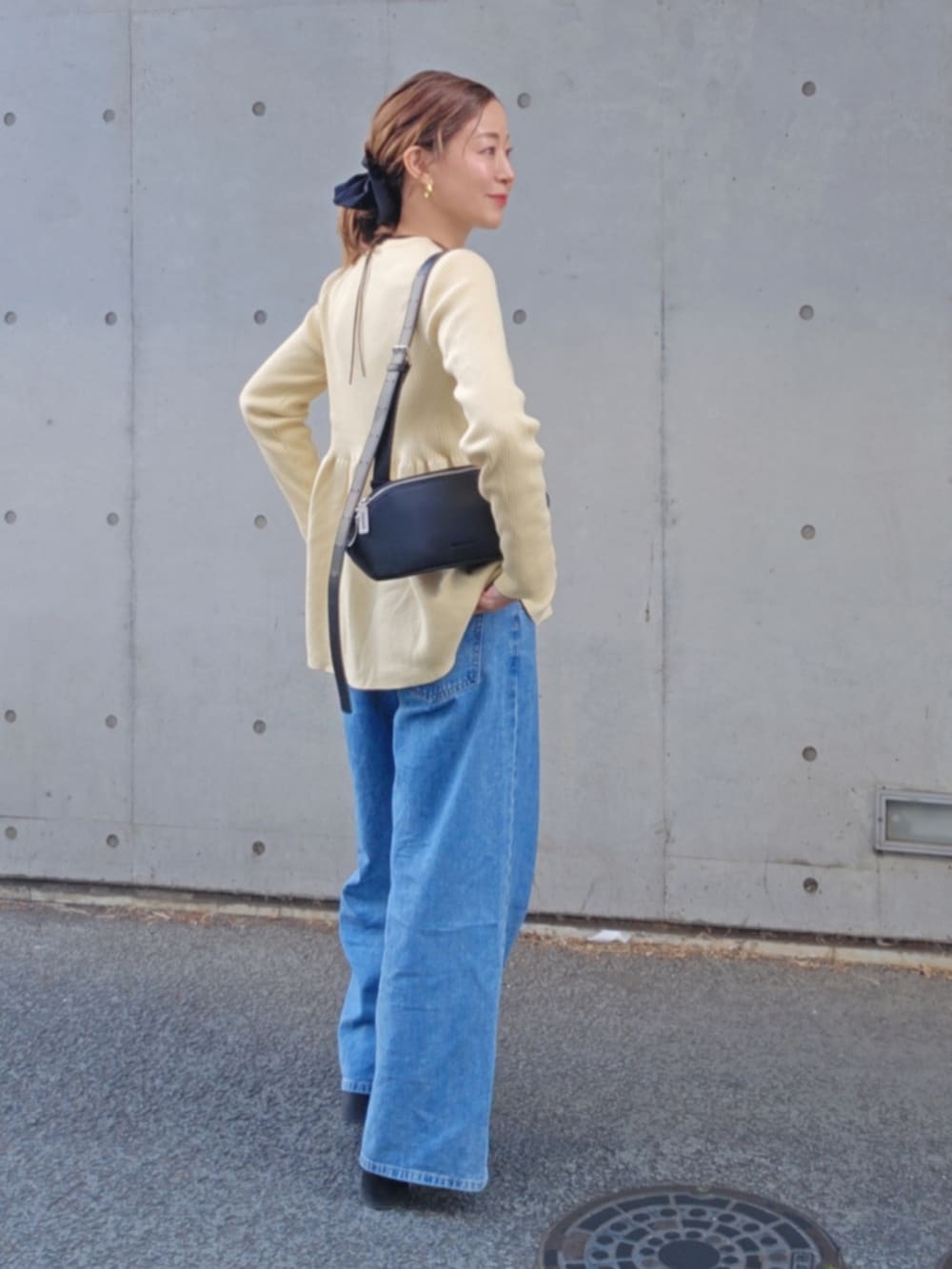 ブラック系のショルダーバッグ、ブルー系のデニムパンツを着用したレディースの春コーディネートの3枚目の写真