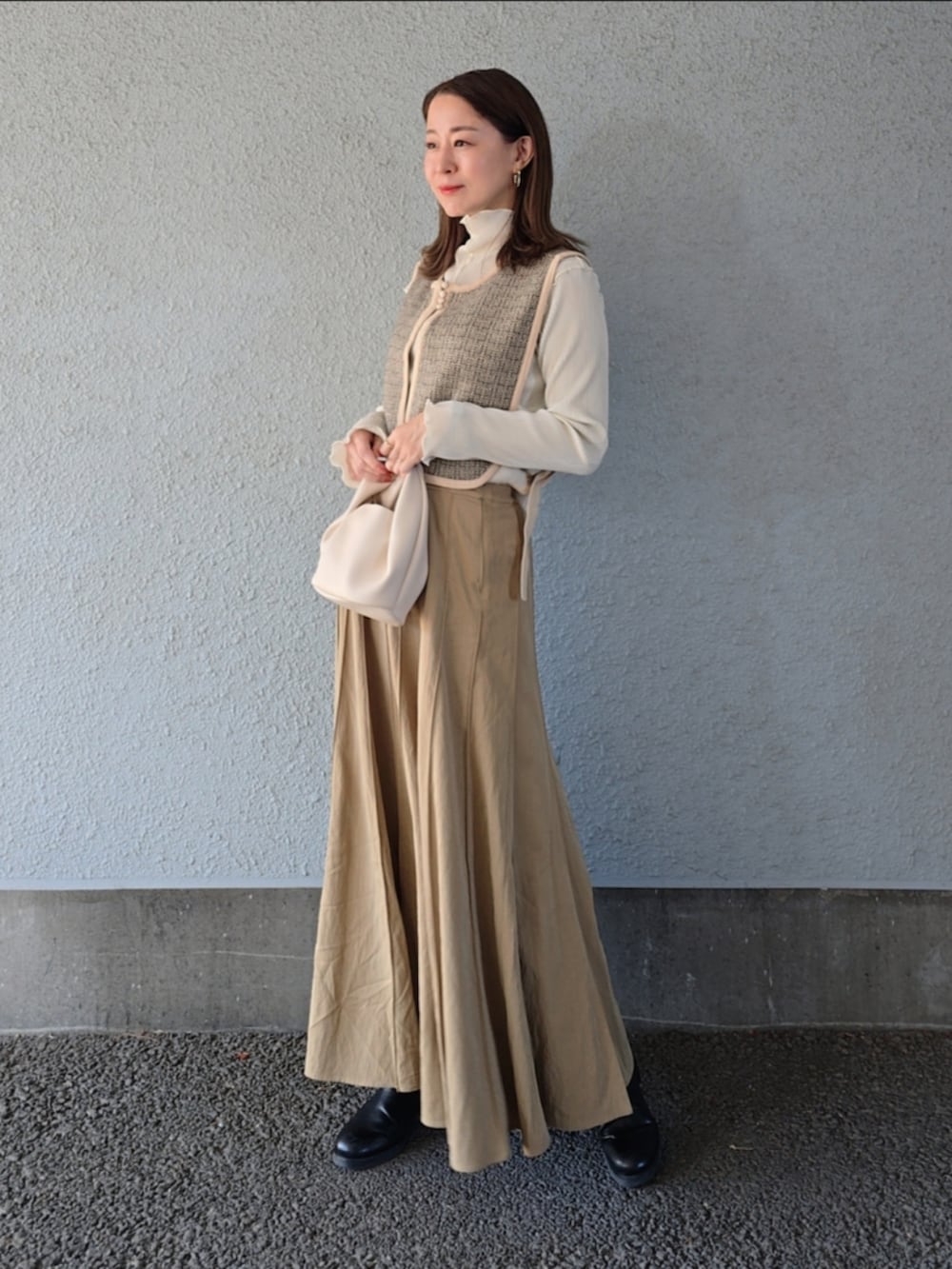 ベージュ系のベスト、ベージュ系のスカート、ブラック系のパンプスを着用したレディースの冬コーディネートの2枚目の写真