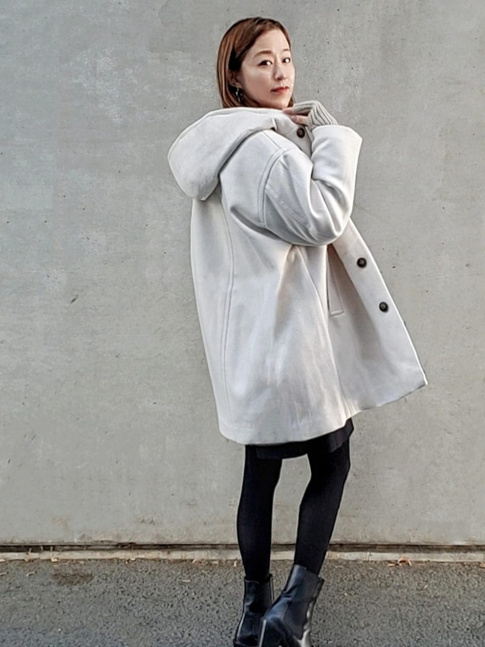 ホワイト系のその他アウター、ブラック系のブーツ、ホワイト系のショルダーバッグを着用したレディースの冬コーディネートの3枚目の写真