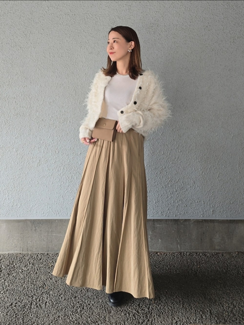 ベージュ系のスカート、ホワイト系のカーディガン/ボレロ、ベージュ系のショルダーバッグを着用したレディースの秋コーディネートの3枚目の写真