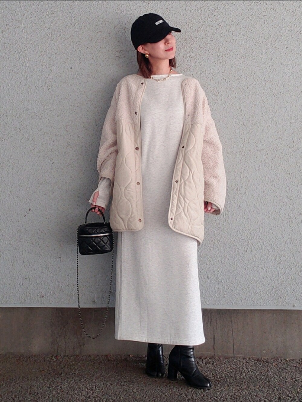 ベージュ系のワンピース、ホワイト系のブルゾン、ブラック系のブーツを着用したレディースの冬コーディネートの2枚目の写真