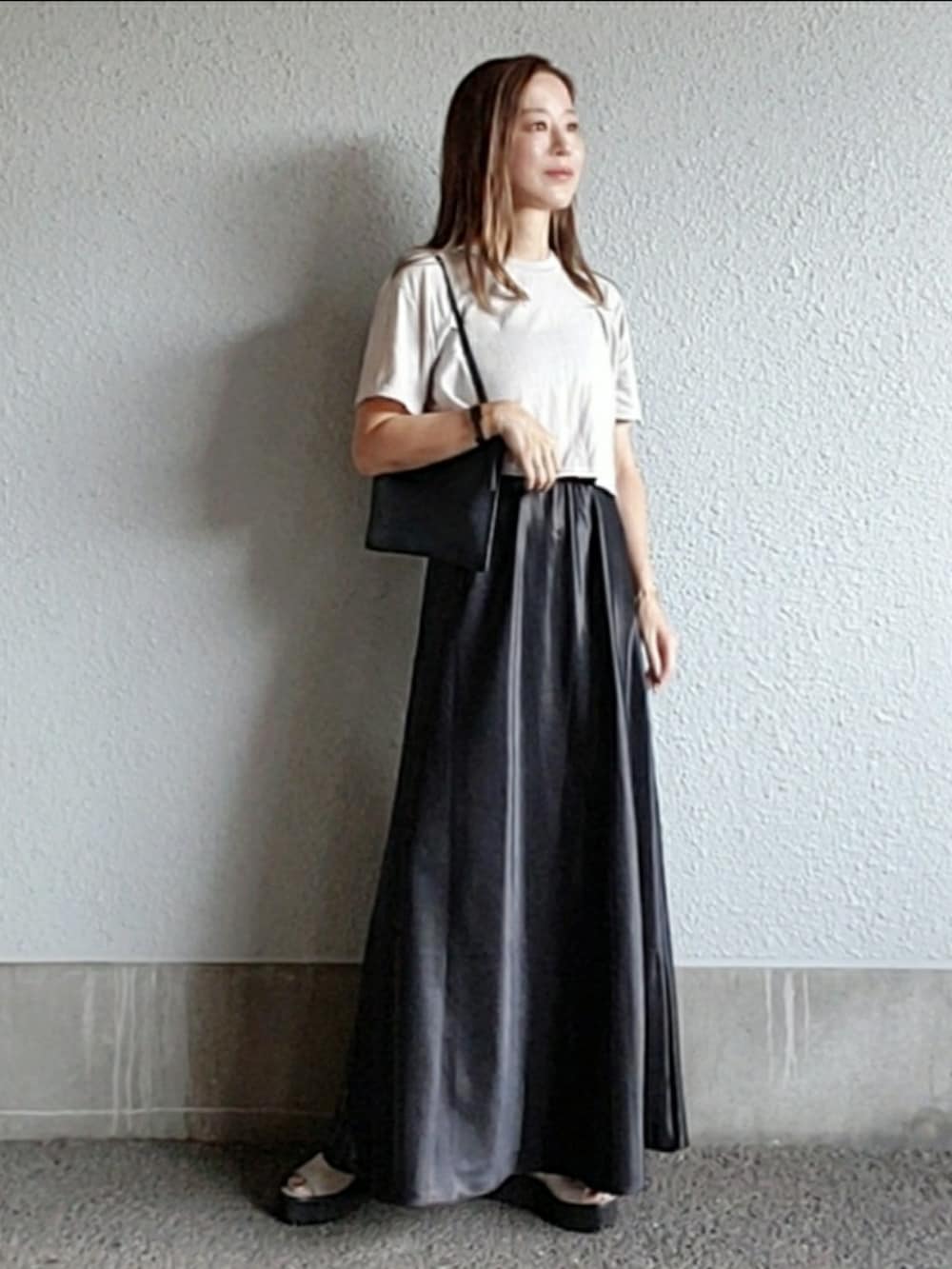 グレー系のTシャツ/カットソー、ブラック系のスカート、グレー系のサンダルを着用したレディースの秋コーディネートの3枚目の写真