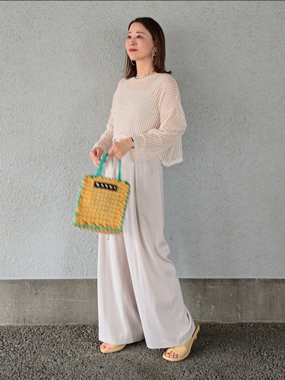 イエロー系のバッグ、ホワイト系のその他パンツ、ベージュ系のニット/セーターを着用したレディースの春コーディネートの2枚目の写真